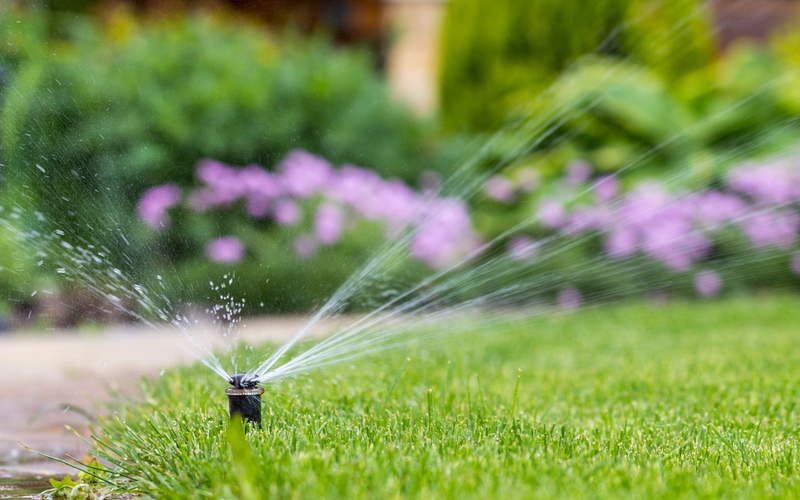 Sprinklers water a beautiful green lawn, thanks to professional sprinkler services in Utah & Arizona provided by Hot Shot Sprinkler Repair & Landscape.