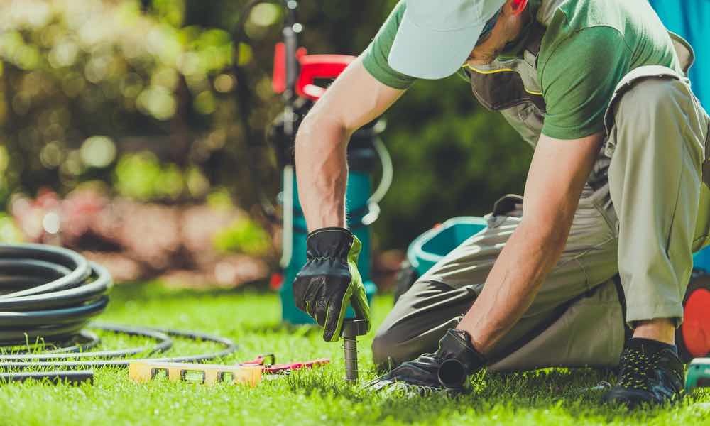 A sprinkler service provider working on a sprinkler system - service provided by Hot Shot Sprinkler Repair & Landscape.